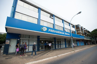 Pessoas caminham em frente a um banco em uma cidade movimentada